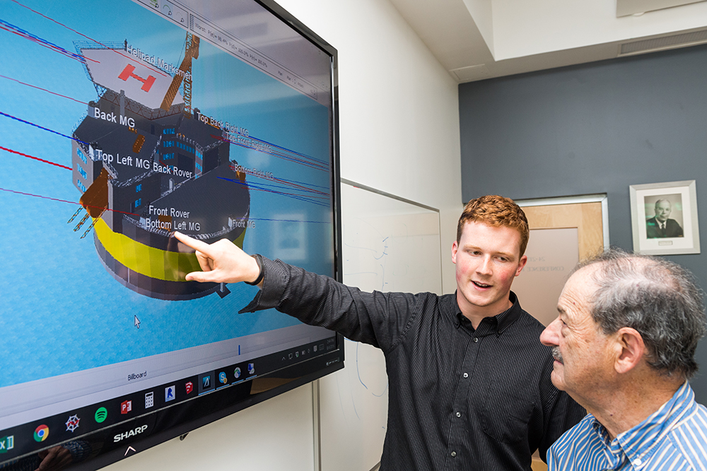 Jared Conway ’19 (left) and his advisor, Professor Neil Todreas of nuclear science and engineering, discuss possible solutions to the special security challenges facing floating nuclear power plants. Photo: Justin Knight